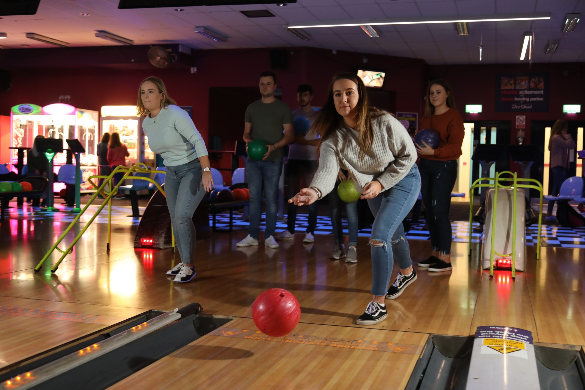 Family watch as little boy pushes bowling ball down kids tenpin bowling aid