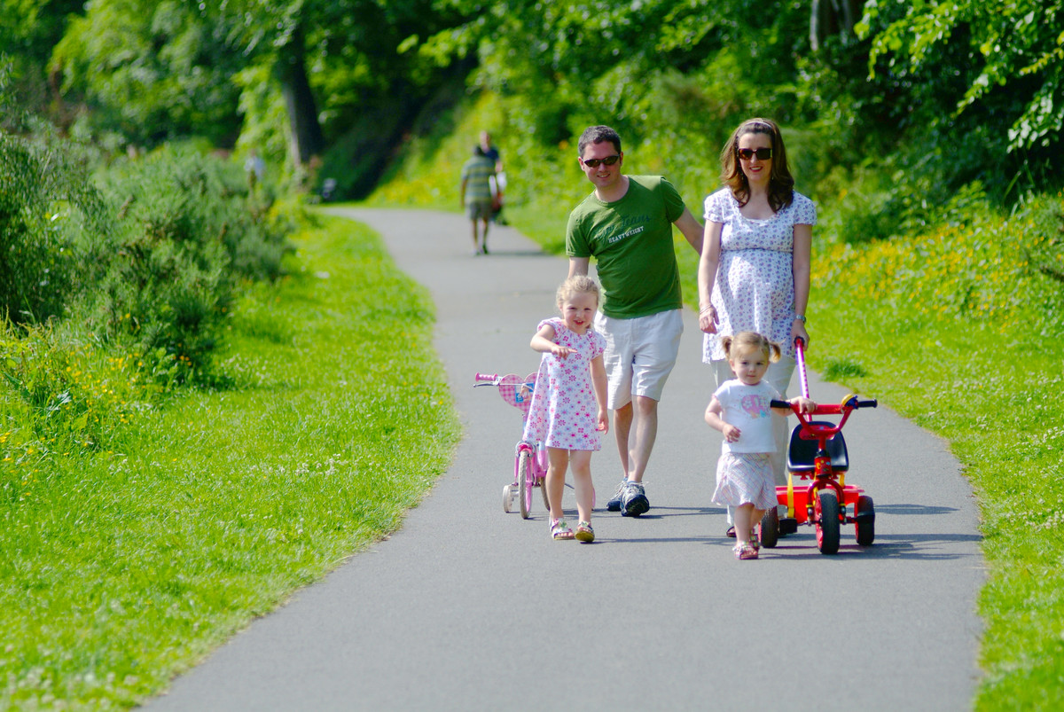 Family walking along path with grass on either side