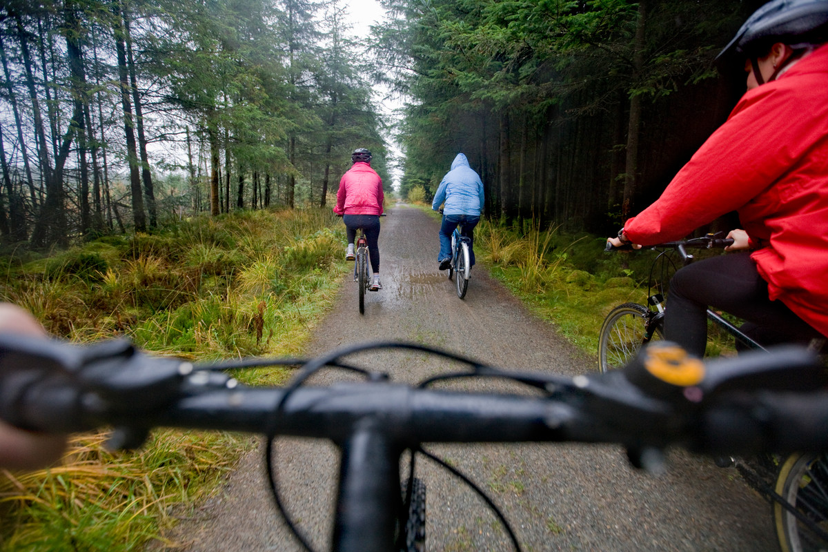 Three people on bicycles, image taken from the point of view of another cyclist, handlebars in foreground