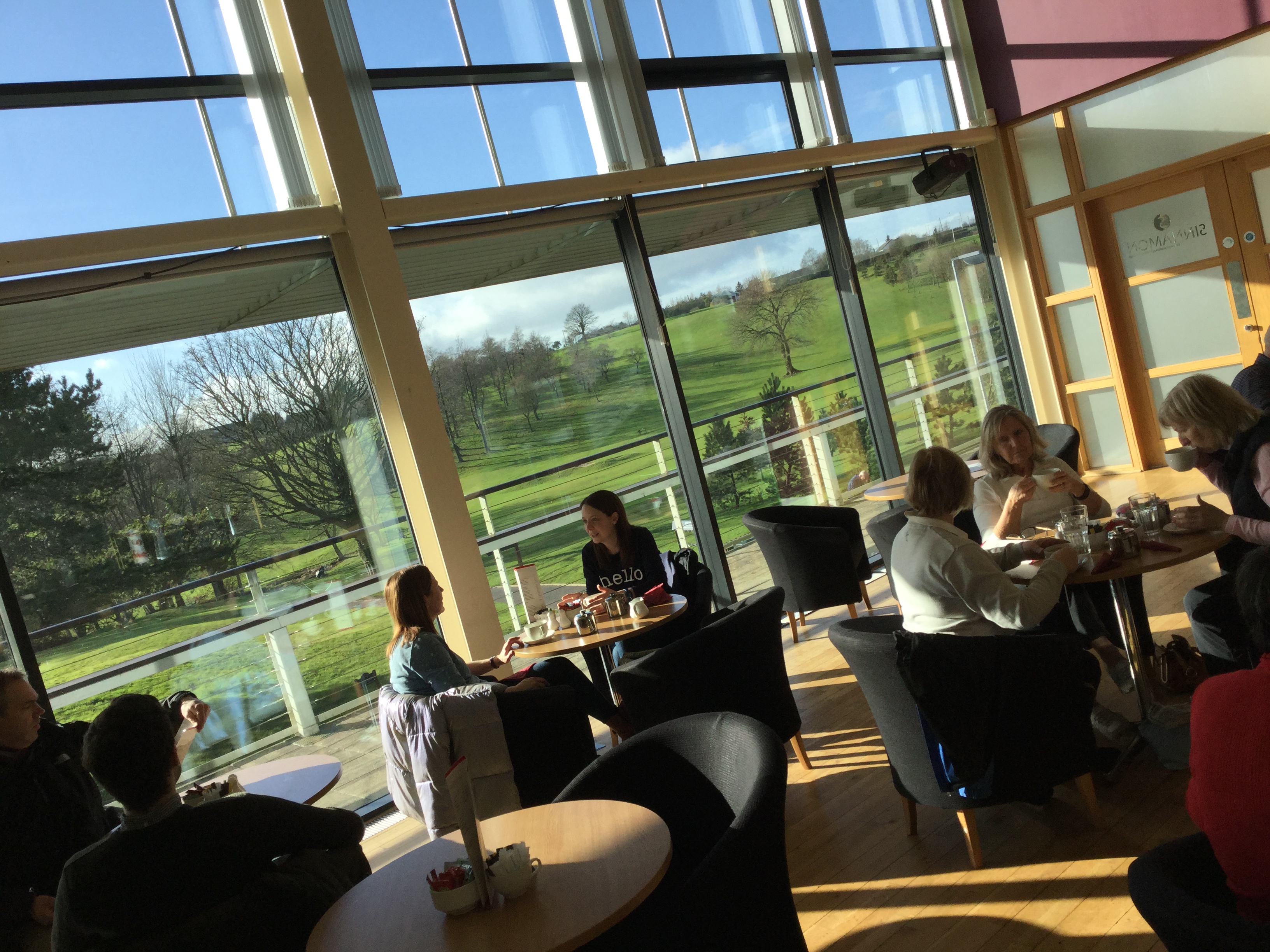 Groups of people sitting at tables eating with large window looking out at golf course