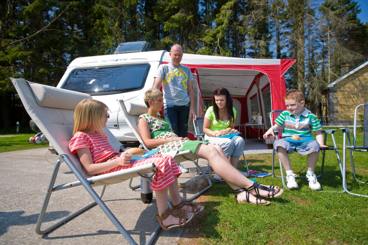 Family of five enjoying lunch outside their caravan