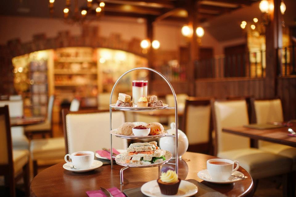 Table with afternoon tea stand filled with cakes, sandwiches, and other sweet treats